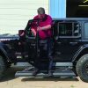 Driver testing electric running boards on a black Jeep Rubicon