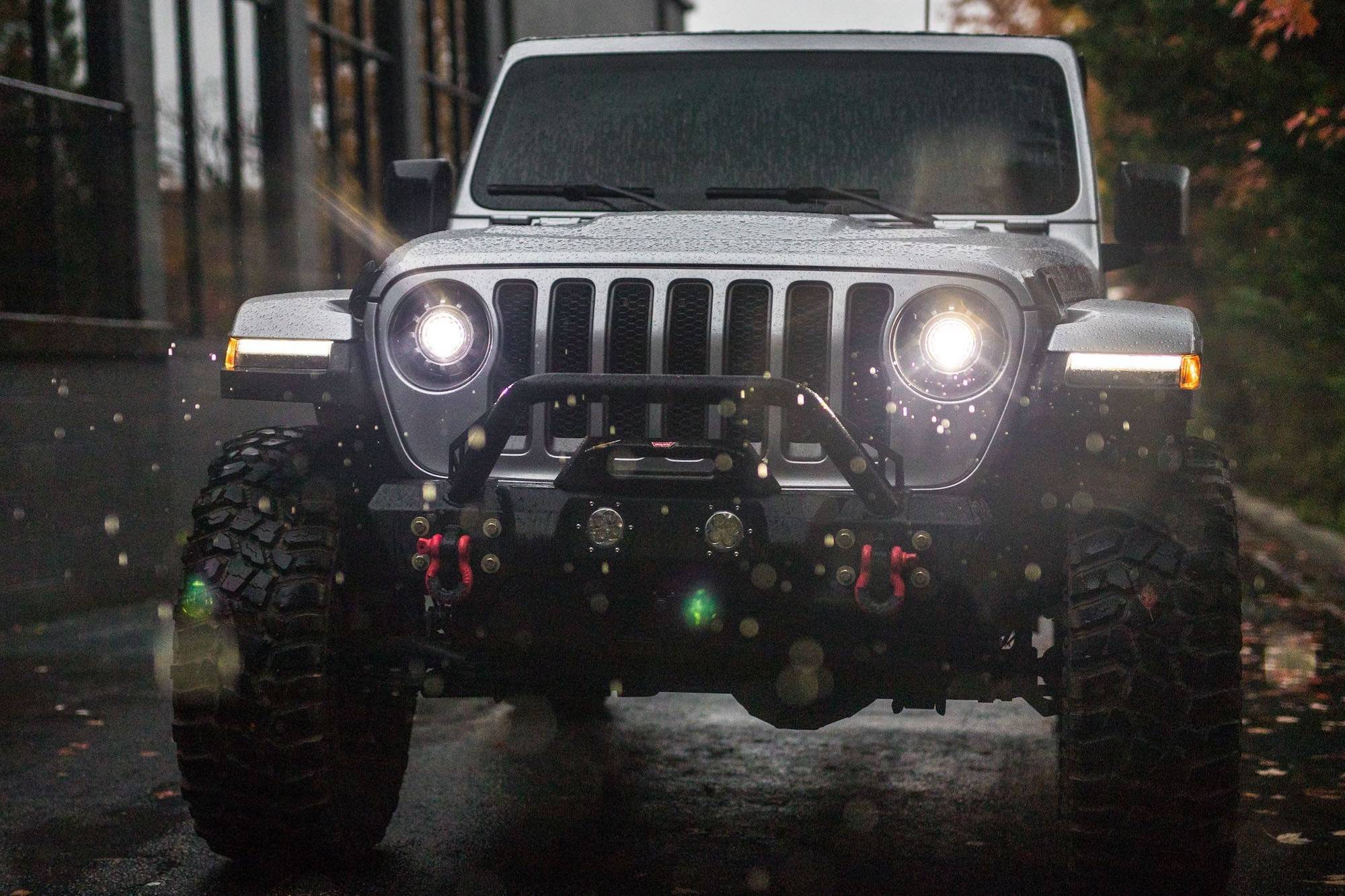 Front view of a Jeep Wrangler with headlights on