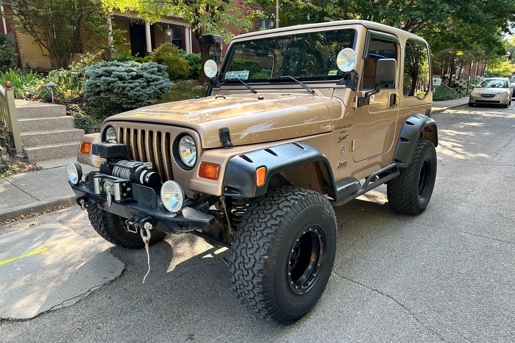 Three-quarter front view of a 1999 gold Jeep Wrangler Sport 4x4