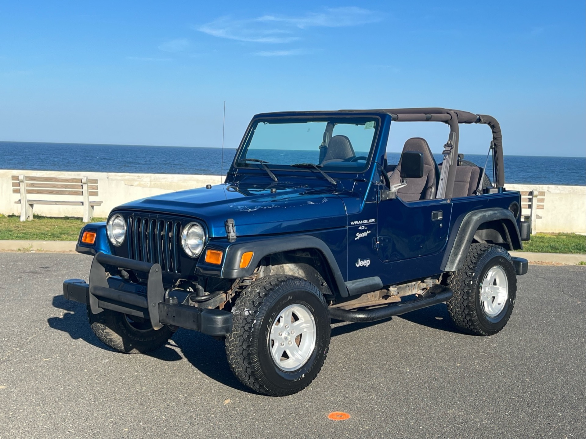 Three-quarter view of a 2001 blue Jeep Wrangler Sport Automatic with ocean background